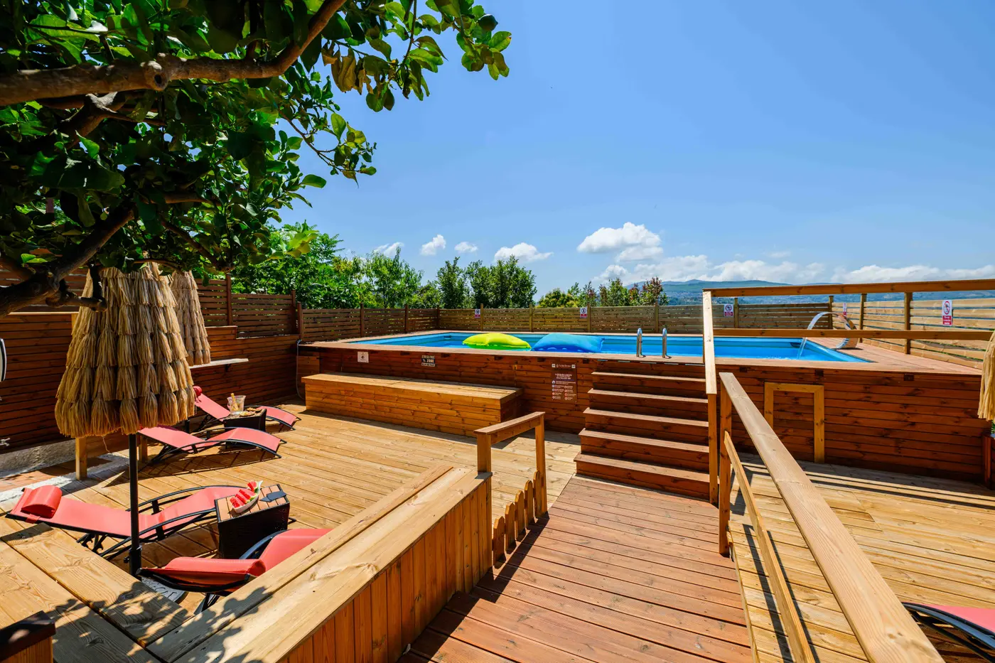 Piscina con solarium in legno e vista sulle colline del Cilento